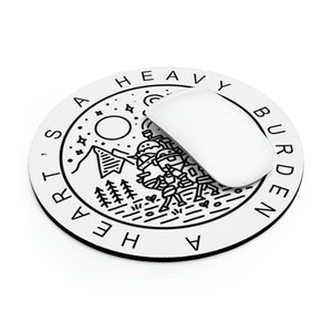 May include: A white round mouse pad with a black outline and a black and white illustration of a mountain range, a moon, stars, and a figure carrying a heavy load. The text "A HEAVY BURDEN'S HEART" is written around the edge of the mouse pad.