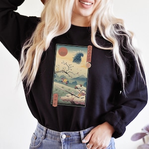 Puede incluir: Una sudadera negra con un estampado gráfico de una escena de la película de anime "La Princesa Mononoke". El estampado presenta un sol rojo, un lobo blanco, un personaje montando al lobo y un gran espíritu azul en el fondo. El texto japonés en el estampado dice "もののけ姫".