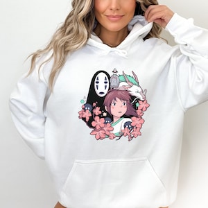Op de afbeelding: Witte hoodie met een grafische print van personages uit de animatiefilm Spirited Away. De afbeelding toont Chihiro, No Face en de draak Haku, omringd door roze kersenbloesems.