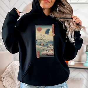 Puede incluir: Sudadera negra con un estampado gráfico de una escena de la película "La Princesa Mononoke". El gráfico presenta un lobo, una joven y un espíritu del bosque. El texto "もののけ姫" está escrito en japonés en el gráfico.