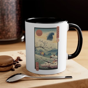 Puede incluir: Taza de cerámica blanca con borde y asa negros. La taza presenta una ilustración de estilo japonés de un personaje montando un lobo con una gran criatura azul en el fondo. El texto "もののけ姫" está impreso en la taza.