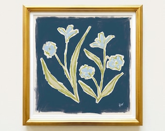 May include: A square framed print featuring a dark navy blue background with two stylized floral stems. The flowers are painted in light blue with pale green leaves and stems. The frame is a metallic gold with a white mat border.