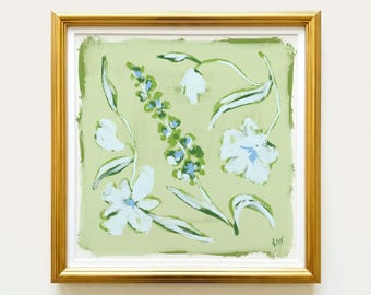 May include: A square painting in a gold frame featuring a light green background with white and blue floral illustrations. The artwork displays various stylized flowers and leaves with visible brushstrokes, and a small signature in the bottom right corner.