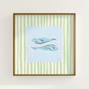 May include: A framed print of two blue fish on a light blue background with green and white stripes around the border.