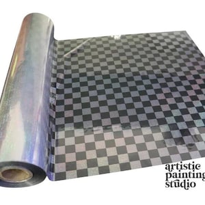 May include: A roll of holographic transfer film featuring a black and silver checkered pattern. The film has a reflective, iridescent surface that shifts colors under light. The text artistic painting studio is printed in the bottom right corner.