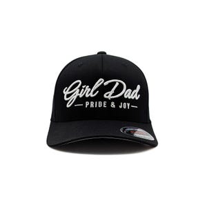 May include: Black baseball cap with the text "Girl Dad - Pride & Joy" embroidered in white script. The cap has a curved brim and a structured fit, suitable for casual wear.