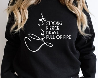 May include: Black sweatshirt with white text that reads "She is strong, fierce, brave, full of fire".