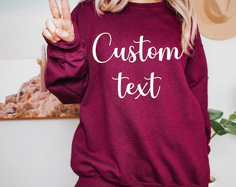 Może przedstawiać: Bordowa bluza z nadrukiem "Custom text" w kolorze białym na przodzie.
