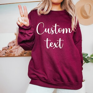 May include: A maroon sweatshirt with the text "Custom text" printed in white on the front.
