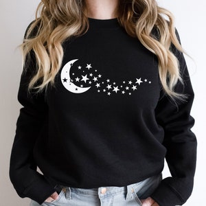 May include: Black sweatshirt with a white crescent moon and stars graphic.
