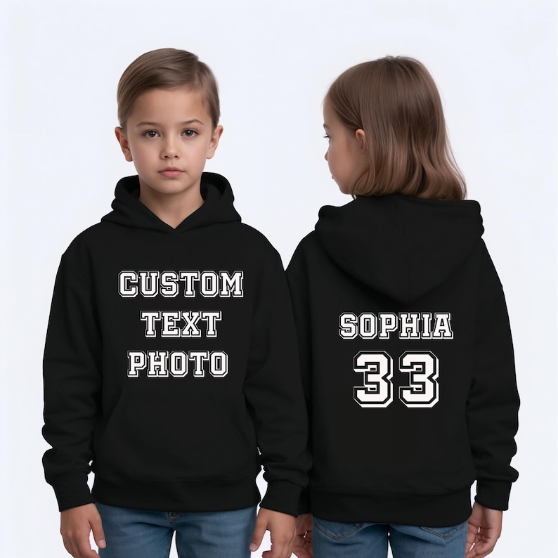 Puede incluir: Sudadera con capucha negra. La parte delantera muestra "CUSTOM TEXT PHOTO" en blanco. La parte trasera presenta "SOPHIA" y el n&uacute;mero "33" en blanco, con una fuente deportiva.