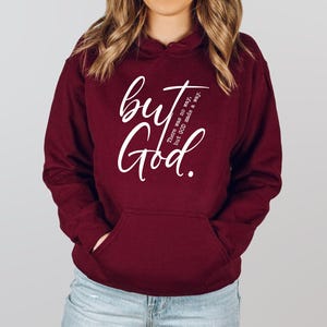 May include: A maroon hoodie with a front pocket and a hood. The hoodie features the white text "but God" in a cursive font, with the phrase "There was no way, but GOD made a way." printed vertically on the right side.