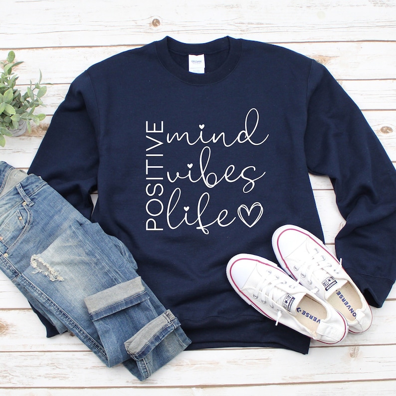 May include: Navy blue sweatshirt with white text that reads "POSITIVE mind vibes life" with a heart symbol.