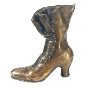 May include: A vintage-style bronze boot shaped decorative object. The boot has a high heel and a button-up design.