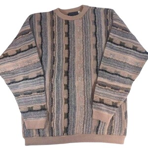 May include: A multi-colored striped sweater with a crew neck. The sweater has a pink, gray, and black color scheme with a geometric pattern.