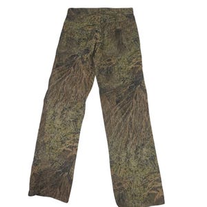 May include: Camouflage pants in shades of green, brown, and tan. The pants have a straight leg design and are made of a durable fabric. The camouflage pattern is designed to blend in with natural environments.