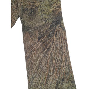 May include: A close-up of a camouflage pattern fabric. The fabric features a blend of brown, green, and tan colors, mimicking a forest environment. The design includes detailed textures resembling branches and foliage, creating a realistic outdoor appearance.