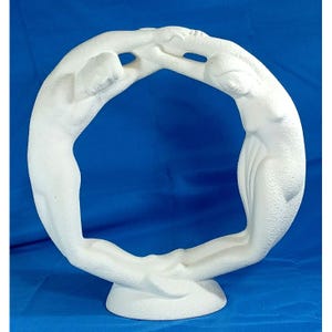 May include: A white sculpture depicting two figures embracing, forming a circular shape. The figures are stylized, with smooth, rounded forms. The sculpture is mounted on a circular base, and the background is a solid blue.