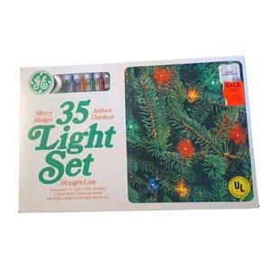May include: A rectangular box for a GE Merry Midget 35 light set, suitable for indoor and outdoor use. The packaging features green text, a graphic of multicolored lights on a pine tree, and a small window showing the included light bulbs.