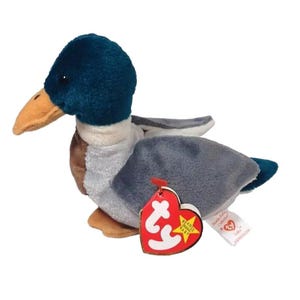 May include: A plush toy duck with a teal head, tan beak, and gray and white body. The duck has a red heart-shaped tag that says "Beanie Baby" and a smaller white tag. The toy is a collectible item.
