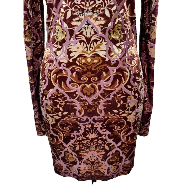 May include: A long-sleeved dress with a burgundy and brown floral pattern. The dress features a detailed design with light purple and tan accents. The fabric appears to be soft and has a velvet-like texture.