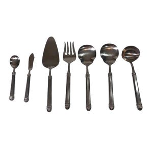 May include: A collection of silver-toned serving utensils, including a spoon, butter knife, cake server, fork, soup spoons, and a ladle. The utensils have a decorative handle design and are arranged against a white background.