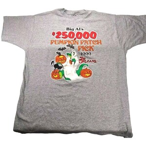 May include: A gray t-shirt with a graphic of a ghost holding a pumpkin. The text on the shirt reads "Big Al's $250,000 Pumpkin Patch Pick 1999 The  Orleans".