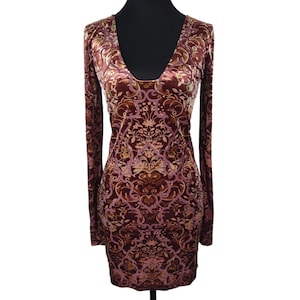 May include: A long-sleeved, bodycon dress in a rich burgundy hue, featuring an intricate floral pattern in shades of gold and mauve. The dress has a deep V-neckline and is made of a soft, velvet-like material.