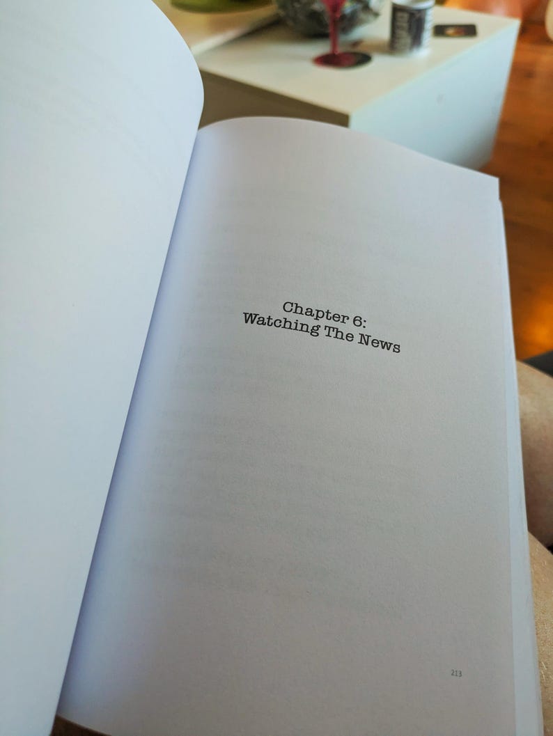 Pu&ograve; includere: Un libro aperto con il testo "Chapter 6: Watching The News" stampato su una pagina bianca. Il libro &egrave; aperto su un capitolo con il numero di pagina 213 visibile. Il libro &egrave; sulle ginocchia di una persona.