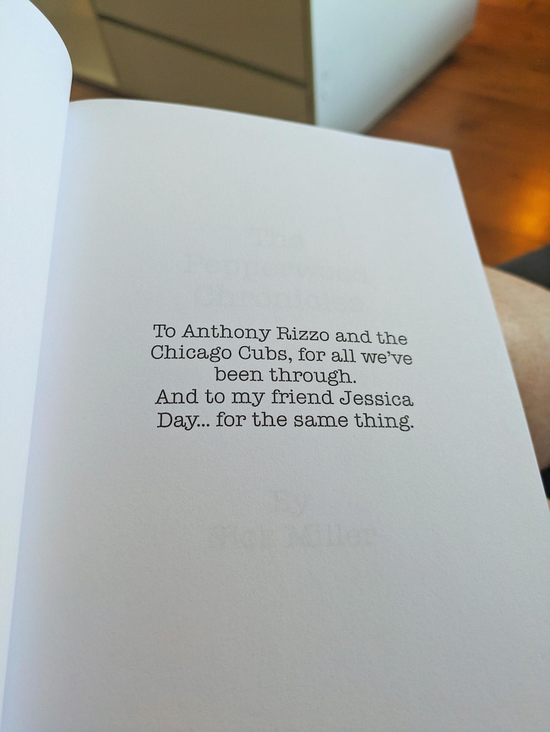 Pu&ograve; includere: Pagina di libro aperta con testo dedicato ad Anthony Rizzo e ai Chicago Cubs, e a Jessica Day. Il testo &egrave; in un semplice font senza grazie, centrato sulla pagina.