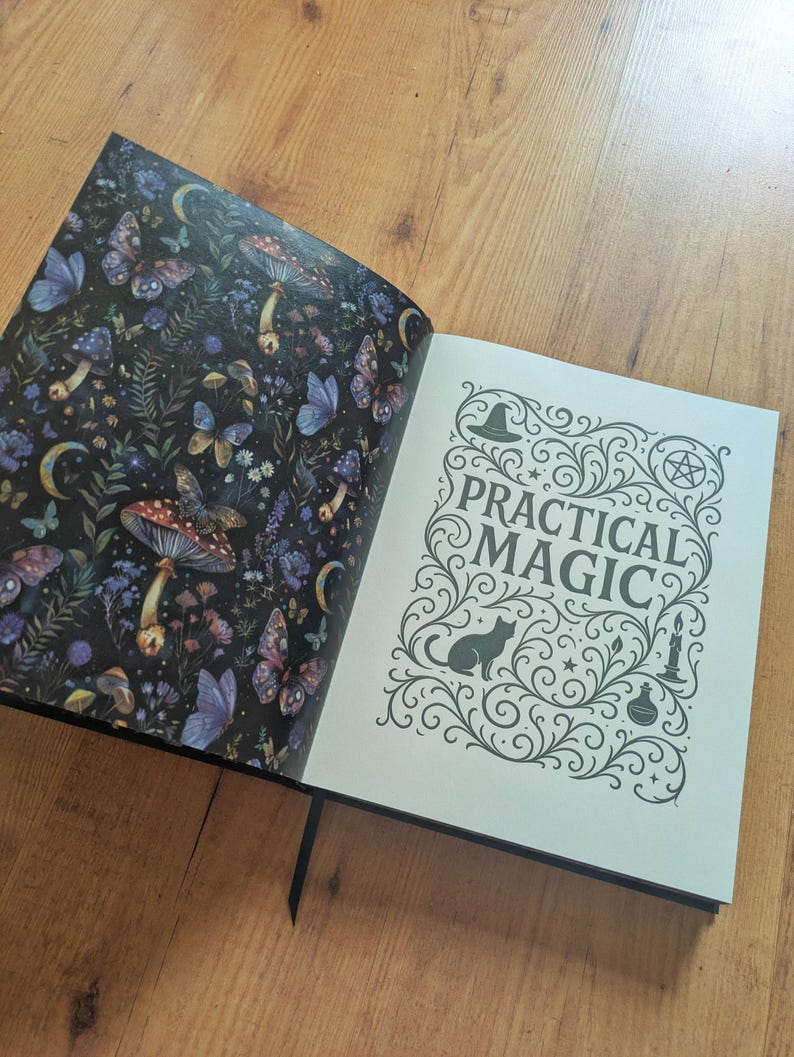 May include: An open book with a black cover, displaying two pages. The left page features a dark background with butterflies, mushrooms, and flowers. The right page reads "PRACTICAL MAGIC" with decorative swirls, a cat silhouette, and a witch's hat.
