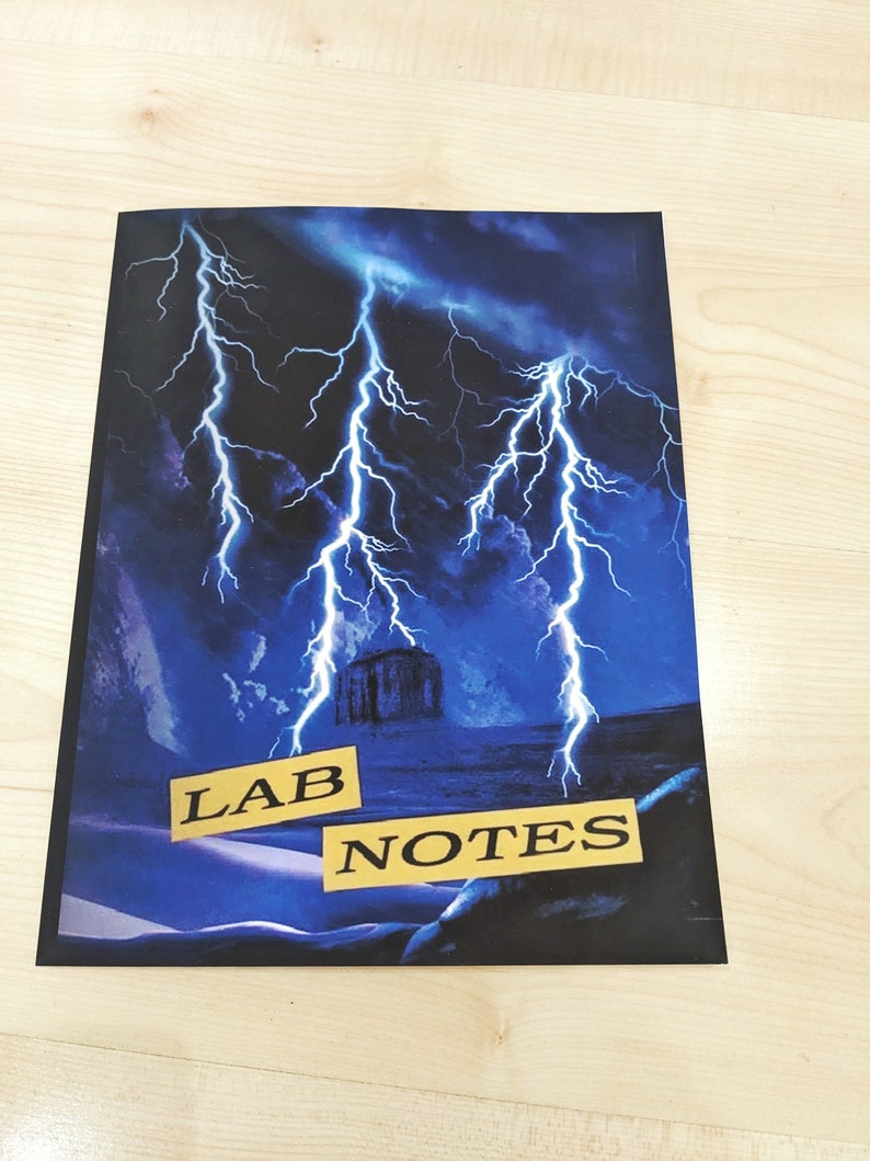 May include: A black notebook with a blue and black lightning storm design. The words "LAB NOTES" are printed in yellow on the cover.