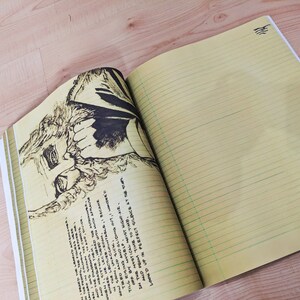 May include: An open notebook with lined yellow pages. The left page has a black and white drawing of a person's face. The right page is blank. The text on the left page reads "AND THE PANAS AND MEASURE THEM WHERE HE LECTURED Now 500N, UNACCOUNTABLE TIRED AND SICK, TILE RISING AND GLIDING OUT, OFF BY MYGELP IN THE MYSTICAL MOIST NIGHT-AI ALD FROM TIME TO TIME, LOOK'D UP IN PERFECT SILENCE AT"