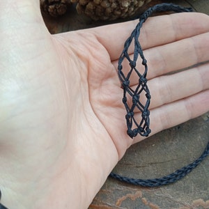 Peut inclure: Un bracelet en macramé noir avec un motif en losange. Le bracelet est fait de cordon et est noué.