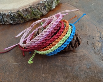 May include: A set of colorful braided bracelets in pink, red, orange, green, and blue. The bracelets are stacked on top of each other and are made with a woven pattern.