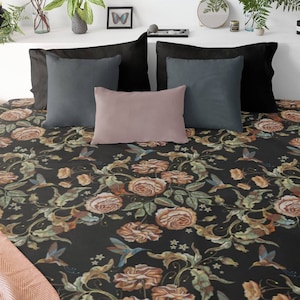 May include: A bed with a black floral patterned comforter and pillows. The comforter features a design of roses, hummingbirds, and foliage in shades of brown, orange, and green. The pillows are in black, gray, and pink. Two wooden nightstands flank the bed.