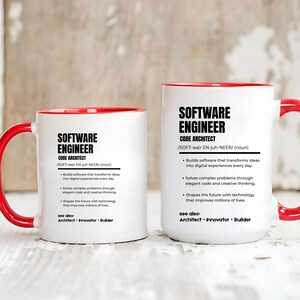K&ouml;nnte beinhalten: Zwei wei&szlig;e Keramikbecher mit leuchtend roten Henkeln und Innenseiten. Jeder Becher ist mit schwarzem Text bedruckt, der einen Softwareentwickler als Code-Architekten definiert, inklusive Lautschrift und stichpunktartigen Aufgaben.