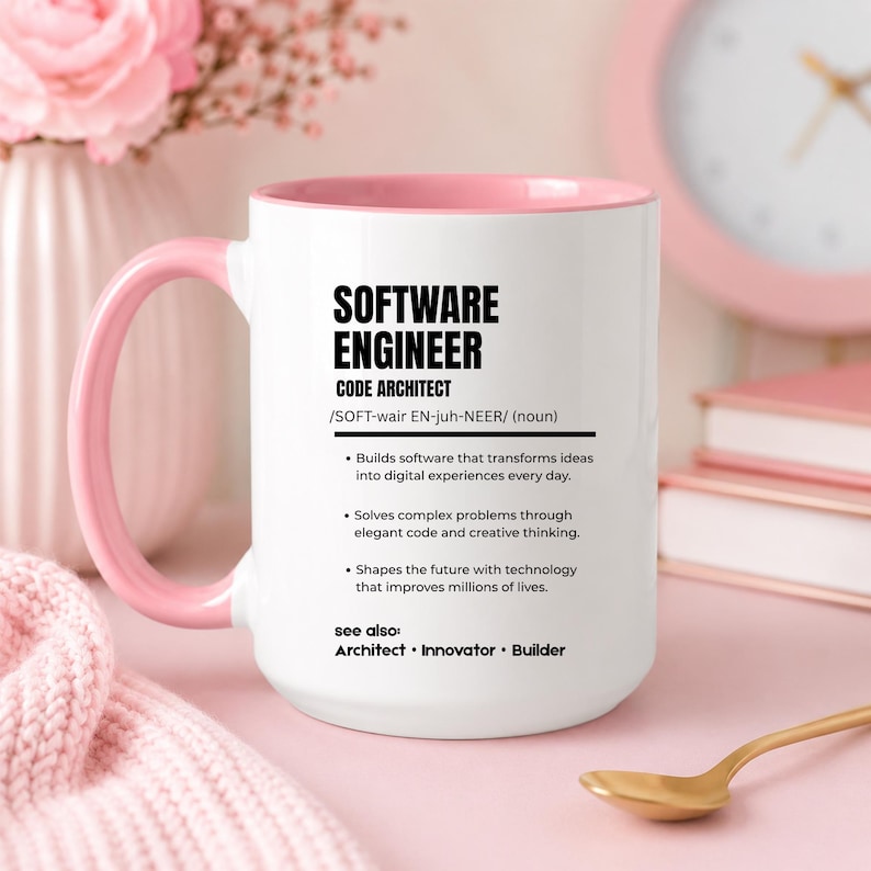 K&ouml;nnte beinhalten: Ein wei&szlig;er Keramikbecher mit einem zartrosa Innenraum und Henkel. Auf der Vorderseite befindet sich ein schwarzer Text, der einen Software-Ingenieur als Code-Architekten definiert, inklusive Aufz&auml;hlungspunkten zu Softwareentwicklung.