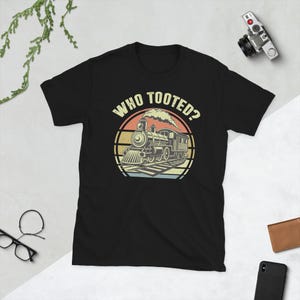 May include: Black t-shirt with a vintage-style graphic of a train with the text "Who Tooted?" in white.