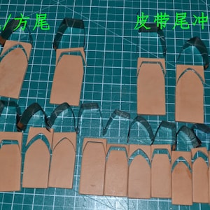 May include: A close-up of leather pieces cut out in the shape of a boot. The pieces are arranged on a green cutting mat with the text "Cut/Shape" and "Leather Boot Knife Pattern" written in black.