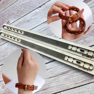 Peut inclure: Deux outils de marquage en cuir en bois avec une surface rainurée et plusieurs trous. Les outils sont utilisés pour créer un bracelet en cuir tressé. Le bracelet est en cuir brun avec une boucle en métal.