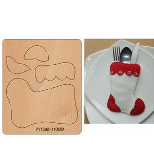 May include: A wooden die-cut template for crafting a Christmas stocking with a red and white design. The template includes a stocking shape, a cuff, and a decorative trim. The template is labeled "YY1602-110MM".