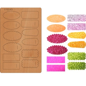 May include: A sheet of wood with various shapes cut out, including ovals, rectangles, and scalloped edges. The sheet is labeled "YY8049".  The image also shows several finished shapes made from glitter paper in various colors, including pink, orange, and green.
