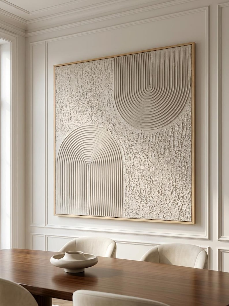 Op de afbeelding: Een groot vierkant wandkunstwerk met een getextureerd gebroken wit oppervlak met twee prominente boogmotieven. E&eacute;n boog bevindt zich rechtsboven en de andere linksonder, beide samengesteld uit verhoogde, parallelle verticale lijnen.