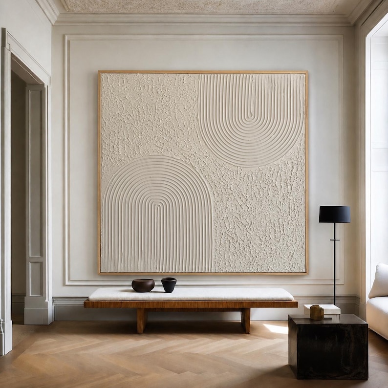 Op de afbeelding: Een groot vierkant wandkunstwerk met een getextureerd cr&egrave;mekleurig oppervlak met verhoogde, uitgesneden boogpatronen. Het kunstwerk is ingelijst in een dunne lichte houten rand en toont een combinatie van gladde groeven en ruwe, onregelmatige delen.