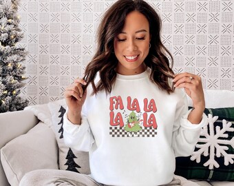 Può includere: Felpa girocollo bianca con un design retrò che dice "FA LA LA LA" in rosso e presenta un albero di Natale che suona la chitarra. Il design è ambientato su uno sfondo a scacchi. Un capo d'abbigliamento festivo per le vacanze.