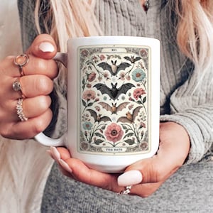 May include: White ceramic mug with a vintage illustration of bats and flowers. The mug features the text "The Bats" and "XII" at the top.