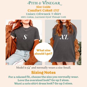 May include: Two models wearing a charcoal grey unisex crewneck t-shirt. The model on the left is wearing a size "S" and the model on the right is wearing a size "XL". The text "Comfort Colors 1717" is displayed above the models. The text "Unisex Crewneck T-shirt" is displayed below the models. The text "100% Cotton, Garment-Dyed Vintage Look" is displayed below the text "Unisex Crewneck T-shirt". The text "What size should I get?" is displayed in a yellow circle in the middle of the image. The text "Model is 5'4" and normally wears a size Small." is displayed below the models. The text "Sizing Notes" is displayed in a yellow box below the text "Model is 5'4" and normally wears a size Small.". The text "For a relaxed fit, choose the size you normally wear. Love the oversized look? Go up 2 sizes. Want a cute shirt dress look? Go up 3 sizes." is displayed below the text "Sizing Notes".