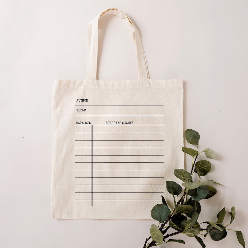 May include: A white canvas tote bag with black text and lines. The text reads "Author", "Title", "Date Due", and "Borrower's Name".