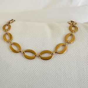 以下が含まれることがあります： 黒い持ち手と「But First, Coffee」のテキストが黒い太字でプリントされた白いセラミックマグ。マグカップはぼやけた背景に置かれており、居心地の良い環境を示唆しています。